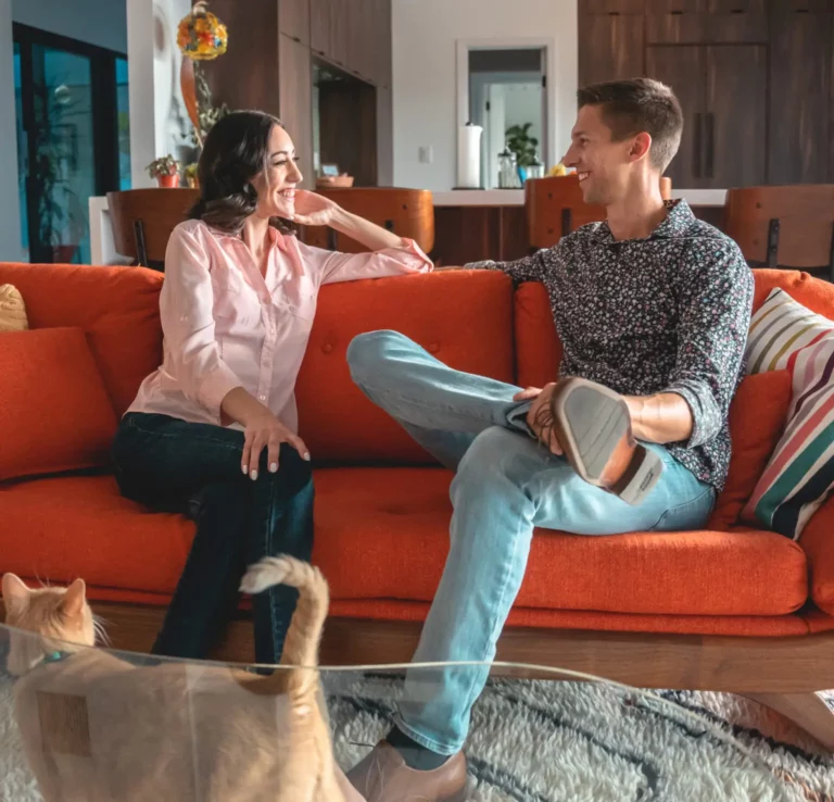 John and Melissa Steele sitting together on an orange sofa at home