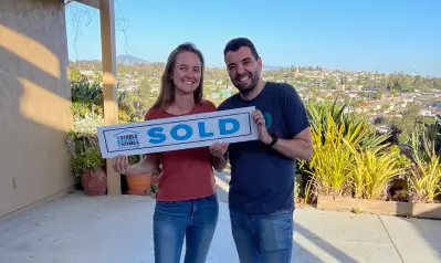Luciano Fraioli and his wife holding a Steele San Diego Homes SOLD sign outside their new home